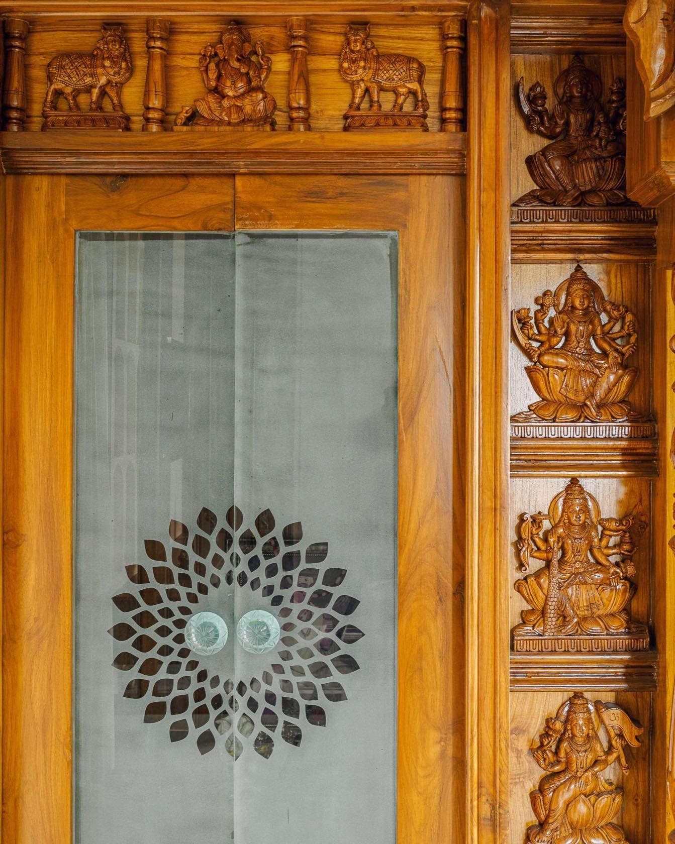 Pooja room glass doors framed in carved teak