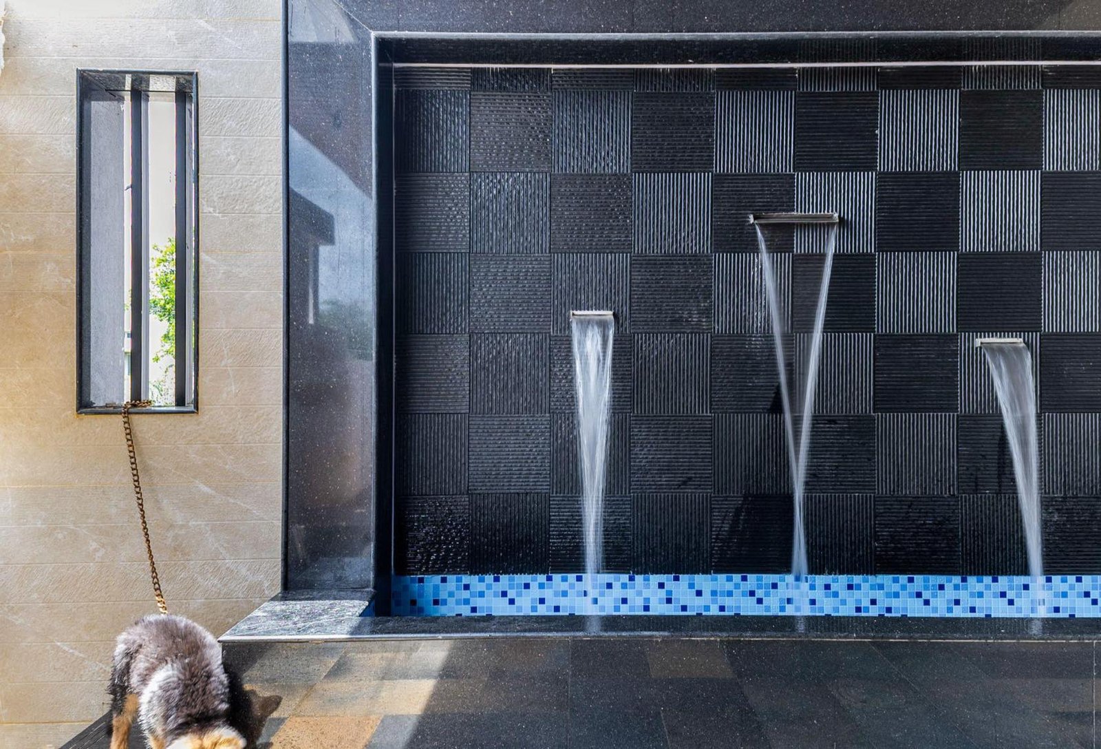 Water feature spouts against a textured stone wall