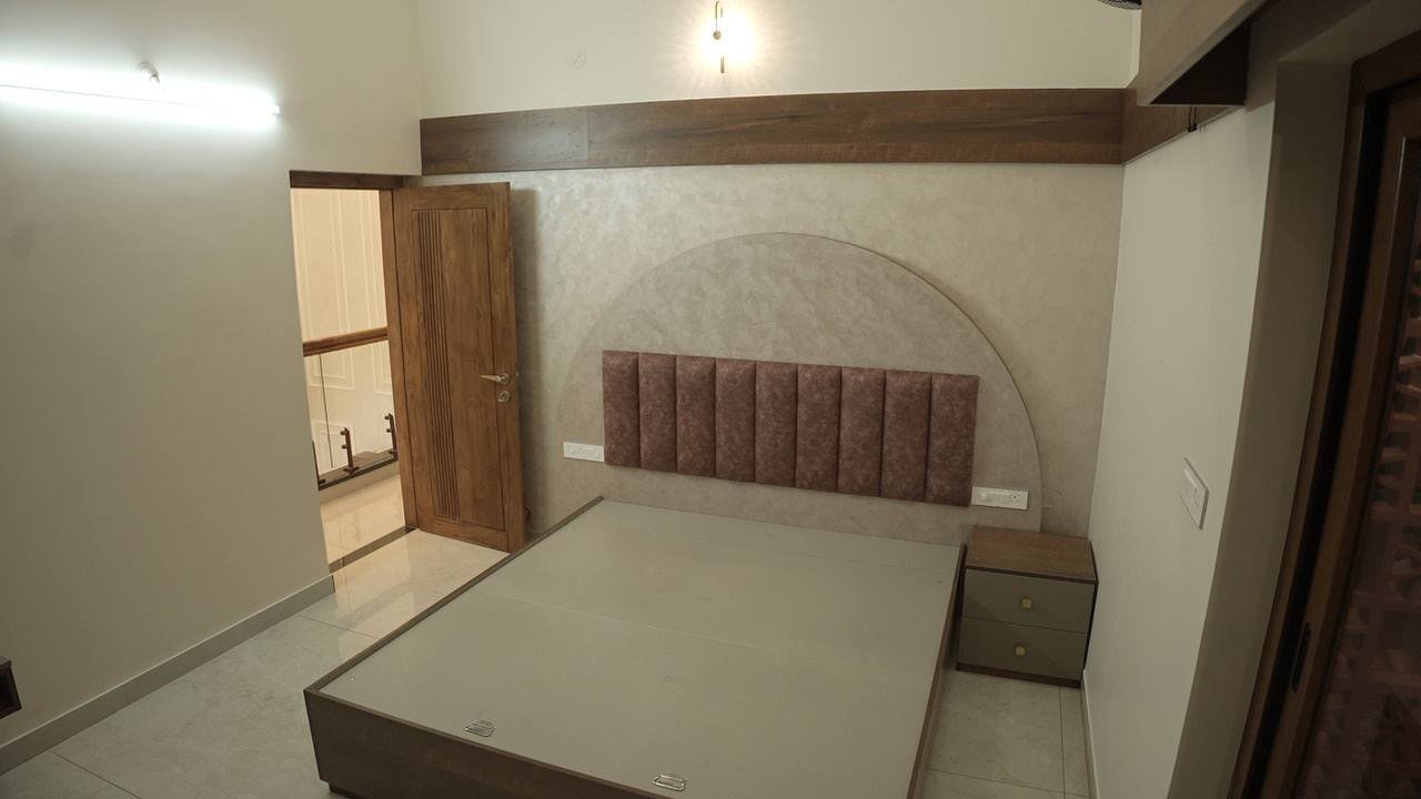 Bedroom with a blush upholstered headboard set against an arched wall panel