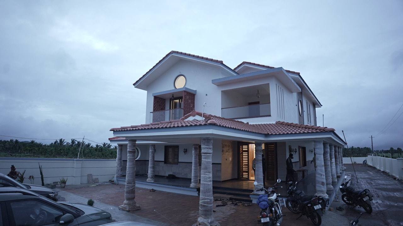 The house at dusk — pitched tiled roofs over a colonnaded veranda