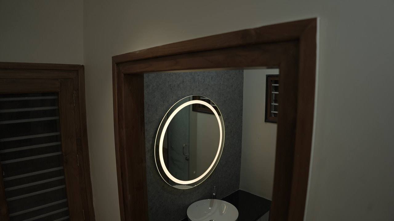 Round backlit vanity mirror framed by a timber doorway